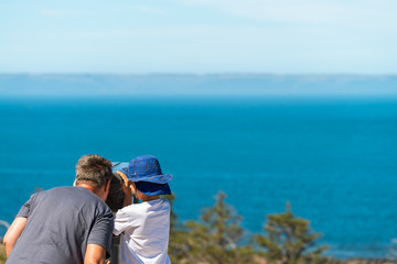 Grandfather and grandson observing Kangaroo Island coast through outdoor binocular