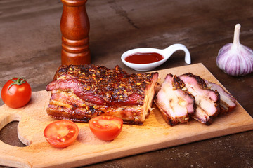 Sliced grilled pork ribs barbecue Striploin steak with chimichurri sauce and tomatoes on cutting board on dark background.