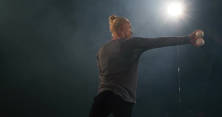 4k - Juggler in the black studio make tricks with balls.
