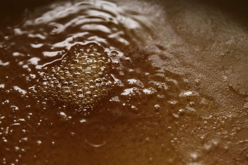 Boiling viscous liquid with orange color and bubbles