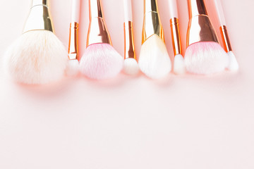 Makeup brushes on pink background. Set of golden makeup brushes, concept. Woman beauty accessory in pastel colors. Copy space. Flat lay