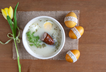 Wielkanocne śniadanie - żurek z jajkiemi i kiełbasą, obok pisanki, koszyczek ze świeconką