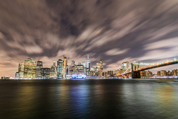 Fototapeta premium Manhattan panoramic skyline at night with Brooklyn Bridge. New York City, USA. Office buildings and skyscrapers at Lower Manhattan (Downtown Manhattan).