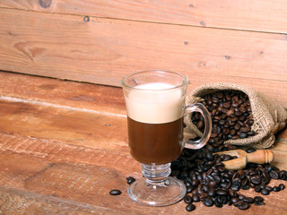 Irish coffee in glass on wooden table. Alcoholic or non-alcoholic coffee cocktail with liqueur, whiskey, cream. Cool drink. Easy Bartenders Recipes and Ideas. Copyspace