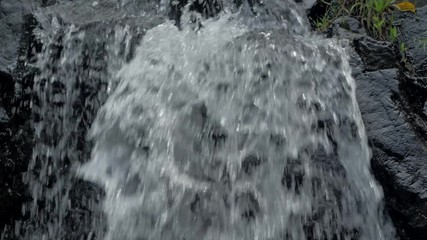 Close-up slow motion shot of small waterfall in the tropical rainforest jungle of Philippines. Small hidden rocky waterfall in jungle valley. Waterfall from a small mountain river in low mountains.