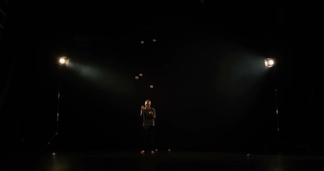 Juggler on the stage makes tricks with 7 ball and have a fail.