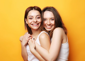 Close up lifestyle portrait of two pretty teen girlfriends smiling hugs and having fun