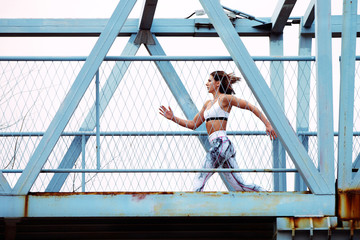 Fototapeta na wymiar Sporty woman who is running in an urban setting over a bridge