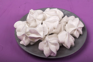 delicious meringue on gray plate on a purple background