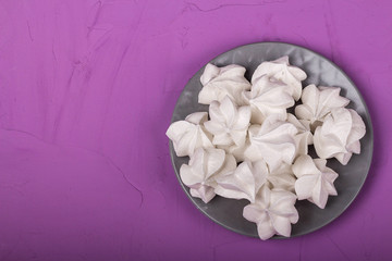delicious meringue on gray plate on a purple background
