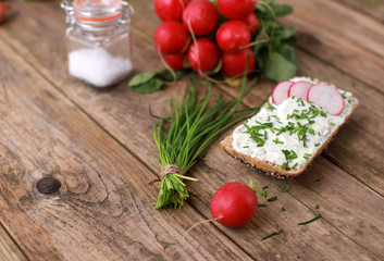 healthy breakfast - wholemeal roll with quark and fresh chive, radish  on a rustic wooden table 