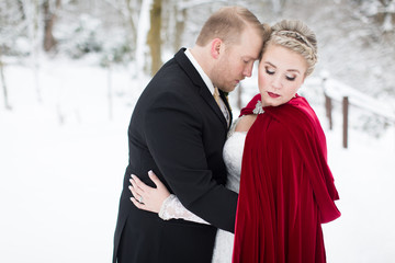 Stunning bride and groom embracing in snow covered woods