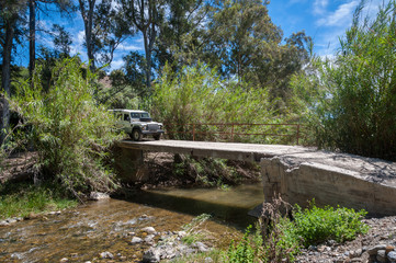 Naklejka premium Rural Andalucia. Spain. 06/10/2016. Driving across river in 4WD on derelict unsecured concrete bridge.
