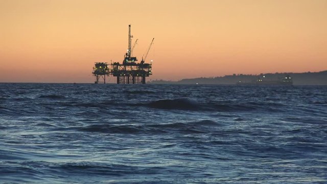 Lights come on at on offshore oil rig at sunset