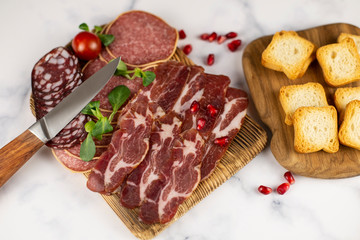 Meat, sausage, toasts and seeds of pomegranate on a marble background