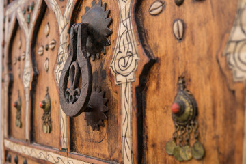 Fototapeta na wymiar Close Up of a Black Iron Door Knocker on a Brown Wooden Door in Marrakech, Morocco