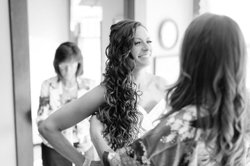 Mother and sister help bride get into dress
