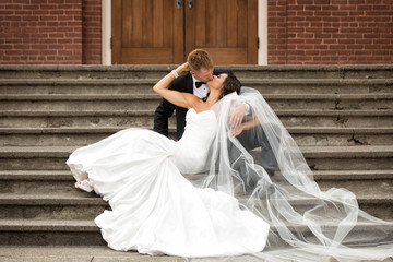 Beautiful bride and groom sensually kissing on church steps
