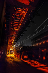 Fototapeta premium Scary urban city alley with elevated illuminated vintage railway tracks at night in Chicago