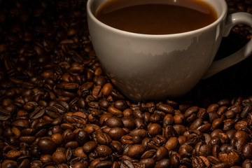 Isolated shot of a cup of coffee surrounded by coffee beans.