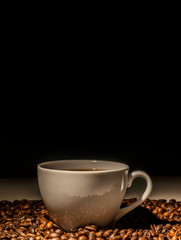 Isolated shot of a cup of coffee surrounded by coffee beans.