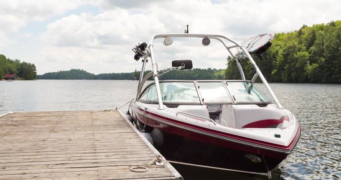 An animated picture of a wakeboard boat at a wooden dock in the Muskokas on a sunny day.