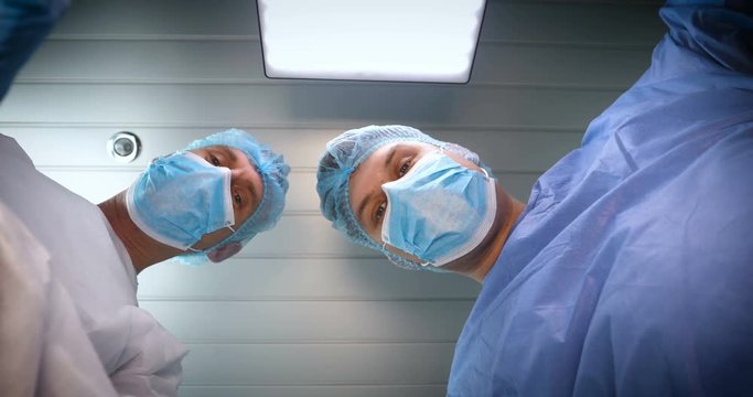 In the hospital, the doctor and the doctor's assistant perform the treatment operation using different medical tools. Both doctors in robes in their headdresses and gloves. Concept of: Dental doctors.