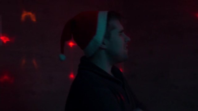 guy in santa hat at a party sings a song, reads rap. Dancing.
