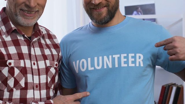 Men pointing at volunteer text on t-shirt, gratuitous help to people in need