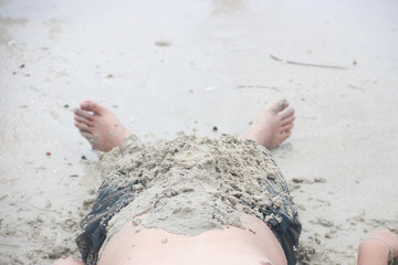 The man lying on the sand at the beach, on vacation.