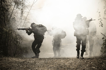 Army patrols in the forest, coming out of the smoke and fog.