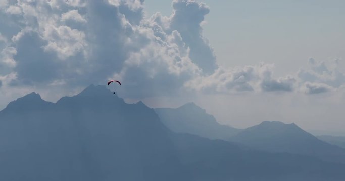 a paraglider is flying above mountains and clouds