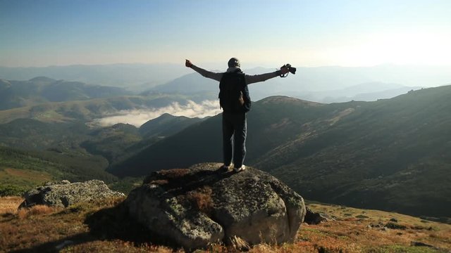 Young man on top of a mountain. Beautiful sunrise landscape