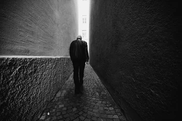 Aluminium Prints Narrow Alley A man in black walking along a narrow alley toward the light. Black and white photography.