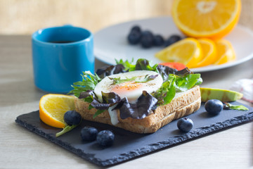 Fried eggs with bread toast on lettuce in a black plate.