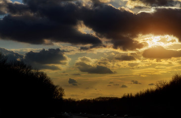sunset in clouds with sunrays over road to horizont