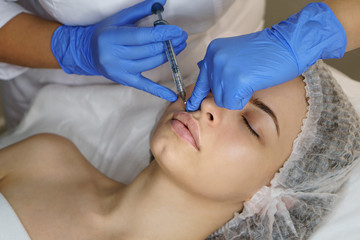 Aesthetic cosmetology. Lip augmentation in spa salon. Beautician makes injections girl in upper...