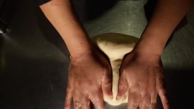 top view of a female chef deflate pizza dough
