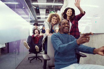multiethnics business team racing on office chairs