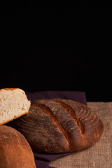 Bakery - gold rustic crusty loaves of bread and buns on black chalkboard background. Still life captured from above