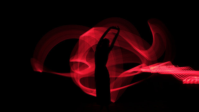 Woman silhouette against red backlight. Light painting photography. Long exposure.
