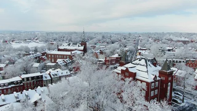 Small town in winter, aerial winter city scape, residential areas with classic red brick homes and a church dominating the skyline, Lancaster, PA in snow