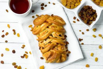 Sweet Braided Bread with raisins on kitchen towel on white wooden background.
