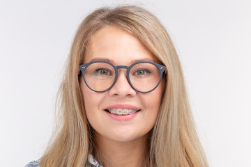 Obraz premium Teeth health, dentistry and bite correction - Happy smiling woman in glasses with braces on white background