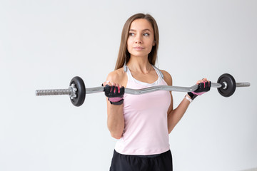 Sport, fitness and people concept - Fit young woman exercises with a weight bar, doing her biceps