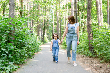 Family, children and nature concept - Portrait of attractive woman and little child girl walking together