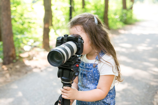 Hobby, profession, children and photographer concept - child with camera in forest