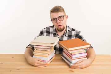 People, exam and education concept - Exhausted and tired student dressed in plaid shirt sitting at the wooden table with many books