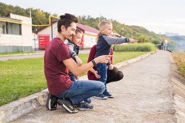 Parenthood, childhood and family concept - Parents and two male children walking at the park and looking on something