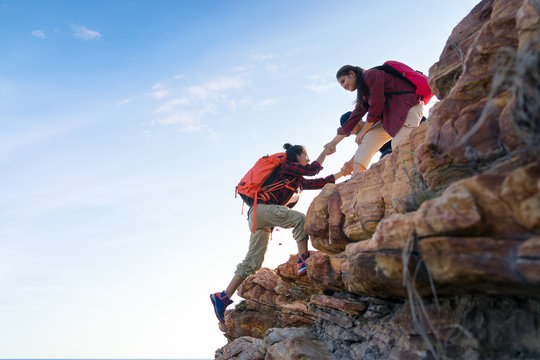 Young asian couple climbing up on the mountain,hiking and team work concept.